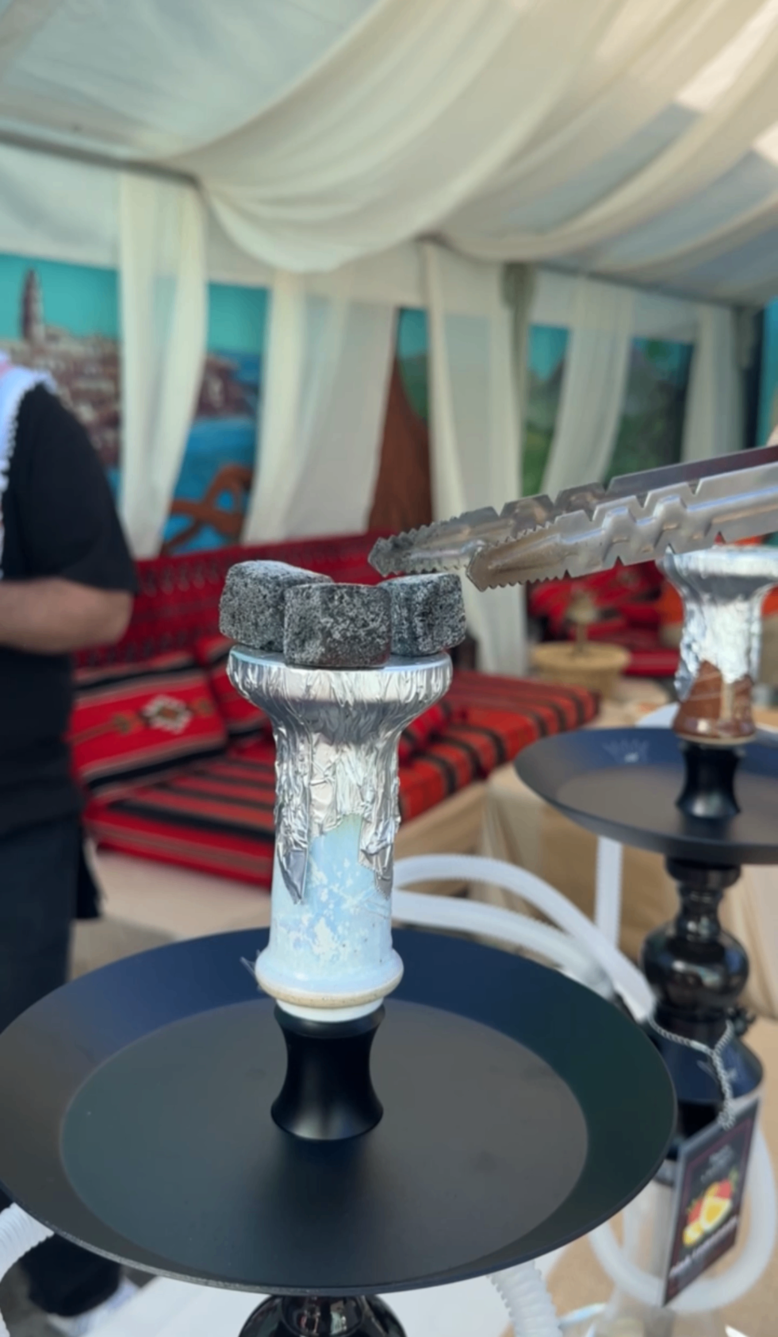 Hookah with stone coals inside a luxury tented cabana setup.