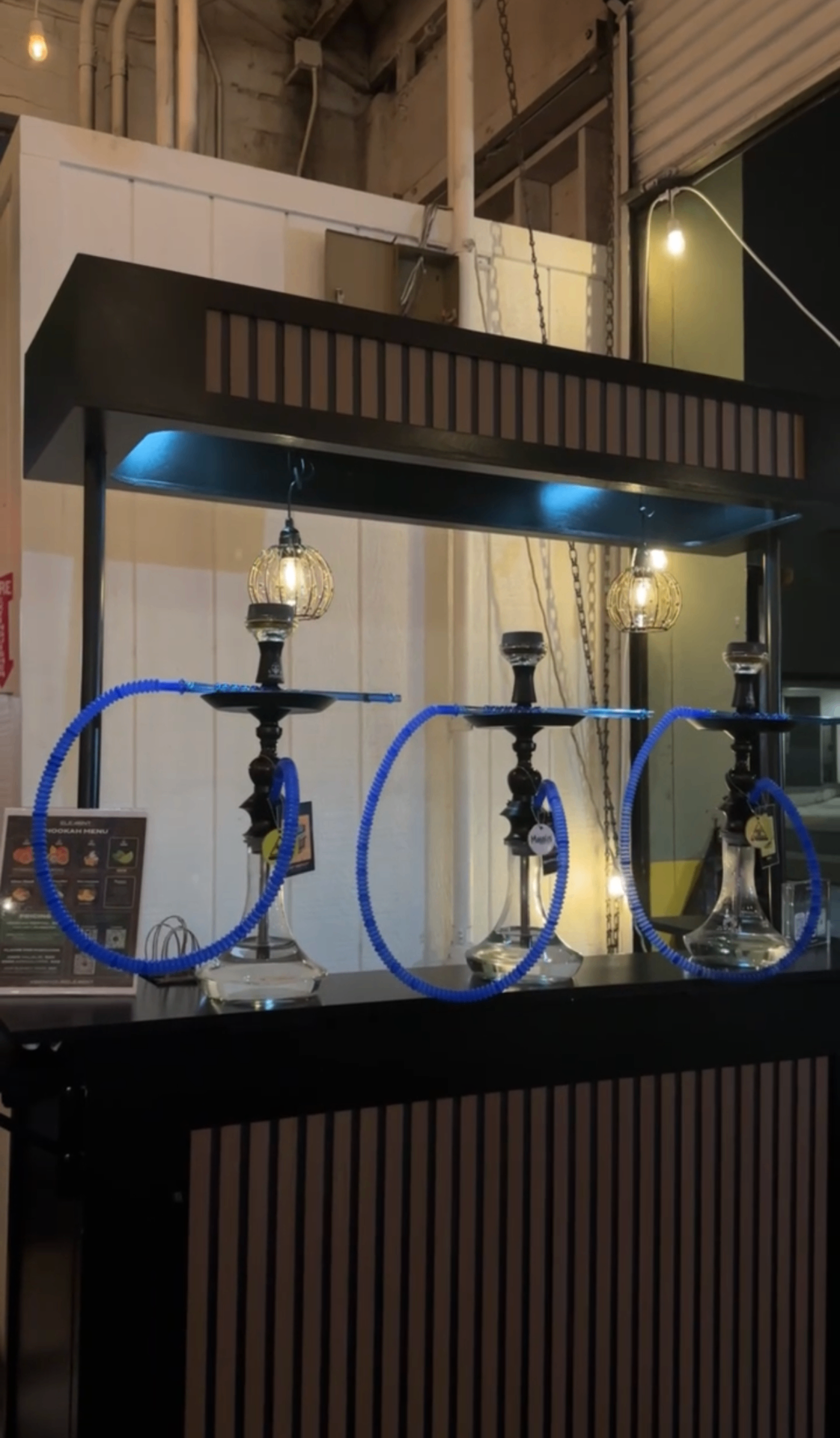 Row of Element hookahs with blue hoses on a branded bar.