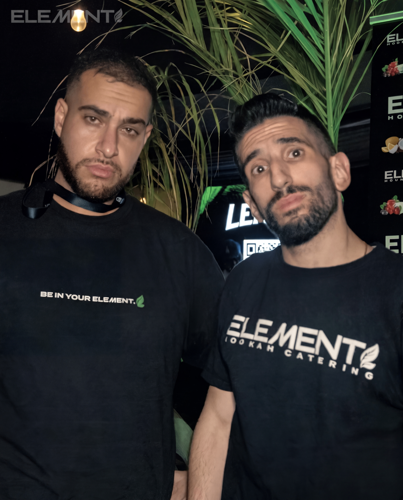 Two team members in Element apparel standing in front of tropical decor.