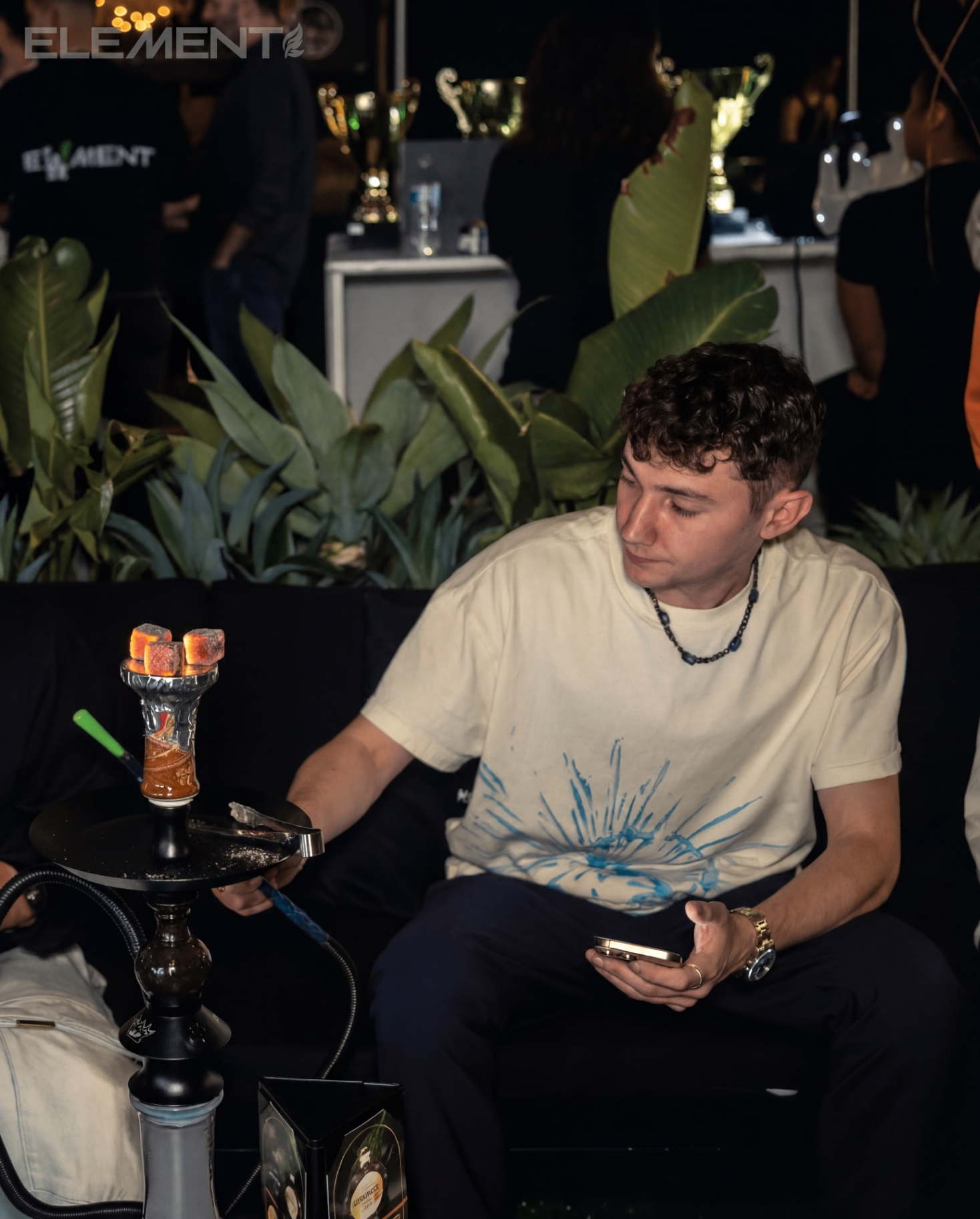 Guest seated beside a lit hookah setup during an evening event.